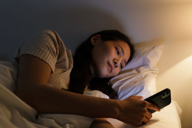 Asian woman checking phone before bed