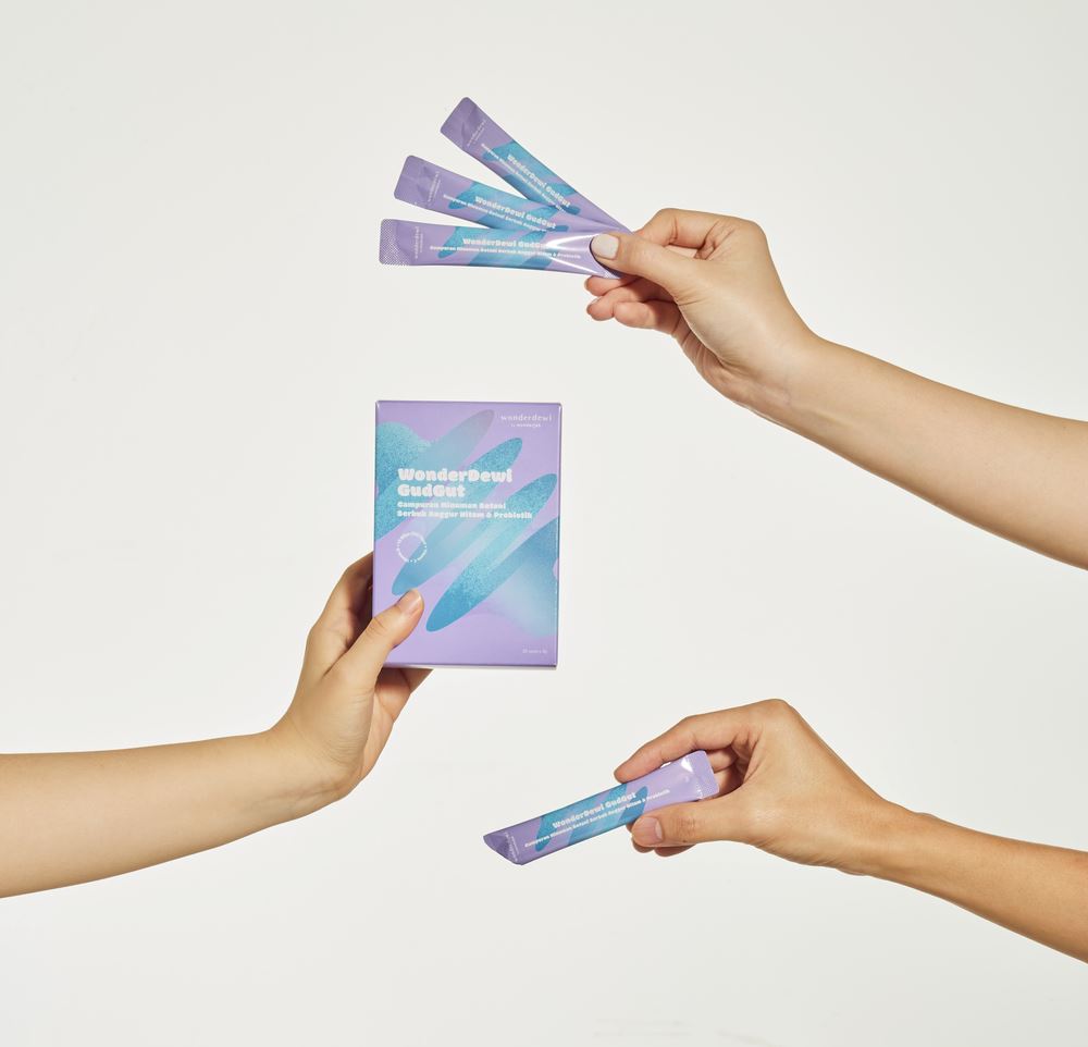 3 hands holding WonderDewi GudGut sachets and box