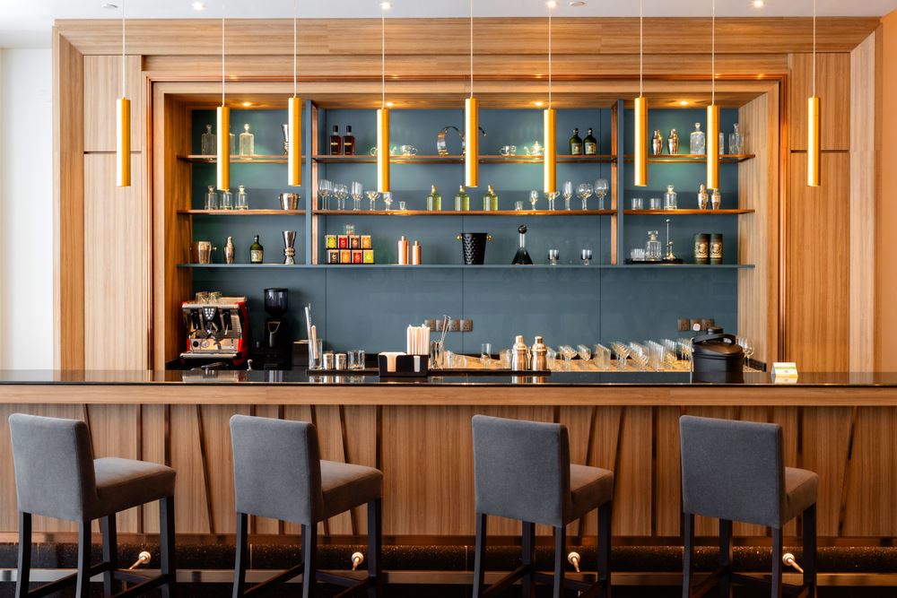 a bar top with chairs and drinks on shelves