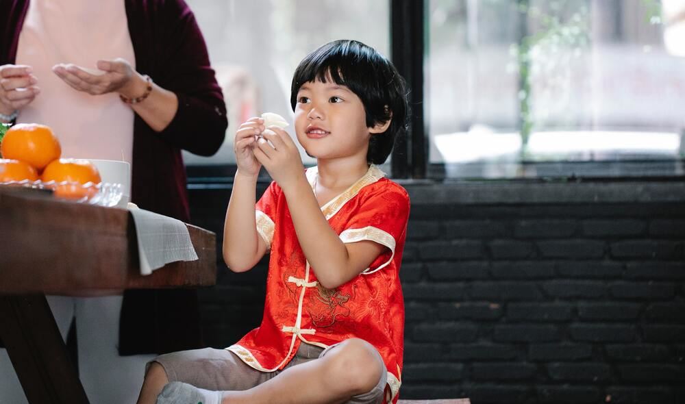 a boy wearing traditional attire while holding food in hand