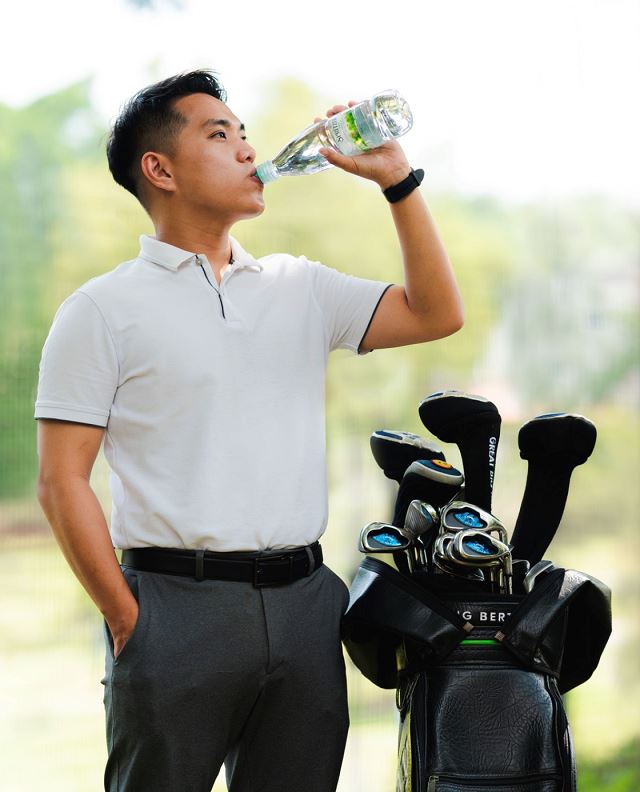 Asian man playing golf and drinking spritzer mineral water