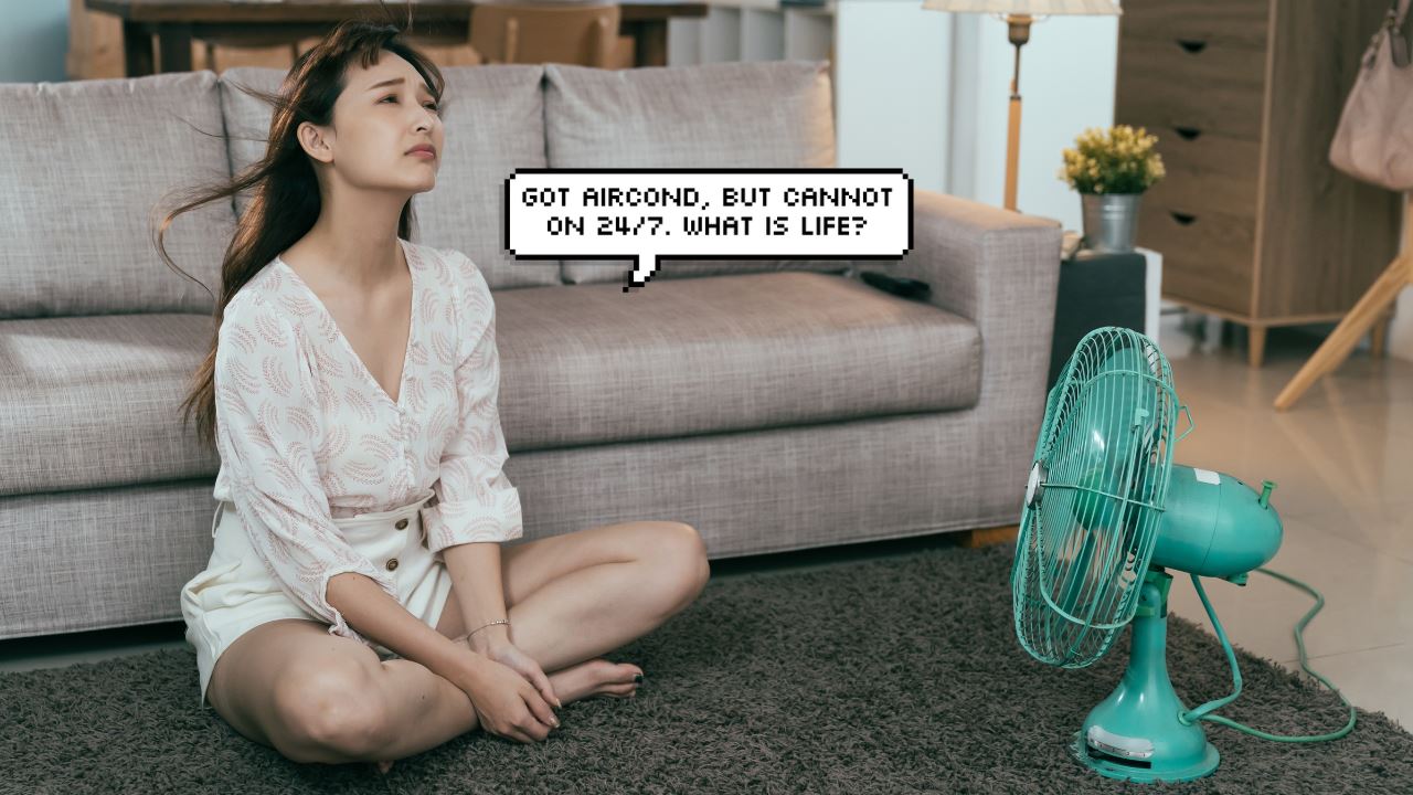 Asian woman sitting in front of fan, uncomfortable with heat