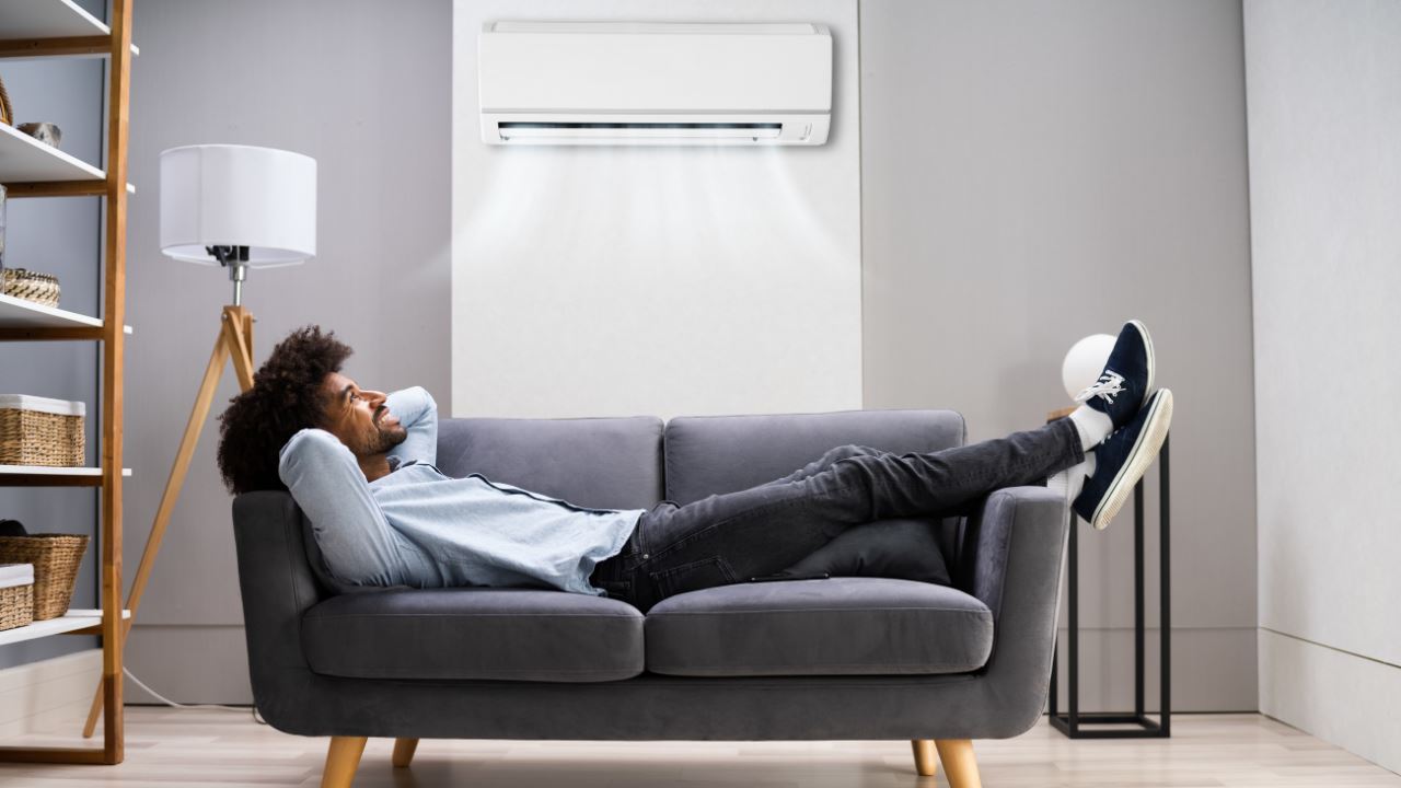 Man relaxing on sofa, enjoying cool breeze of air conditioner