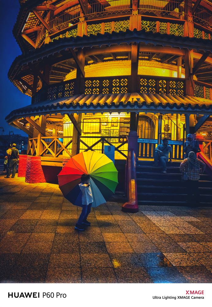 Night view of temple with boy holding colourful umbrella