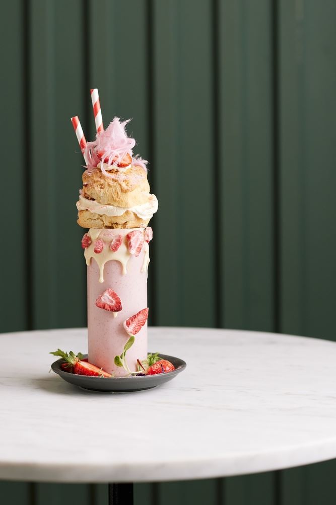 A tall cup of shake with strawberries and ice cream