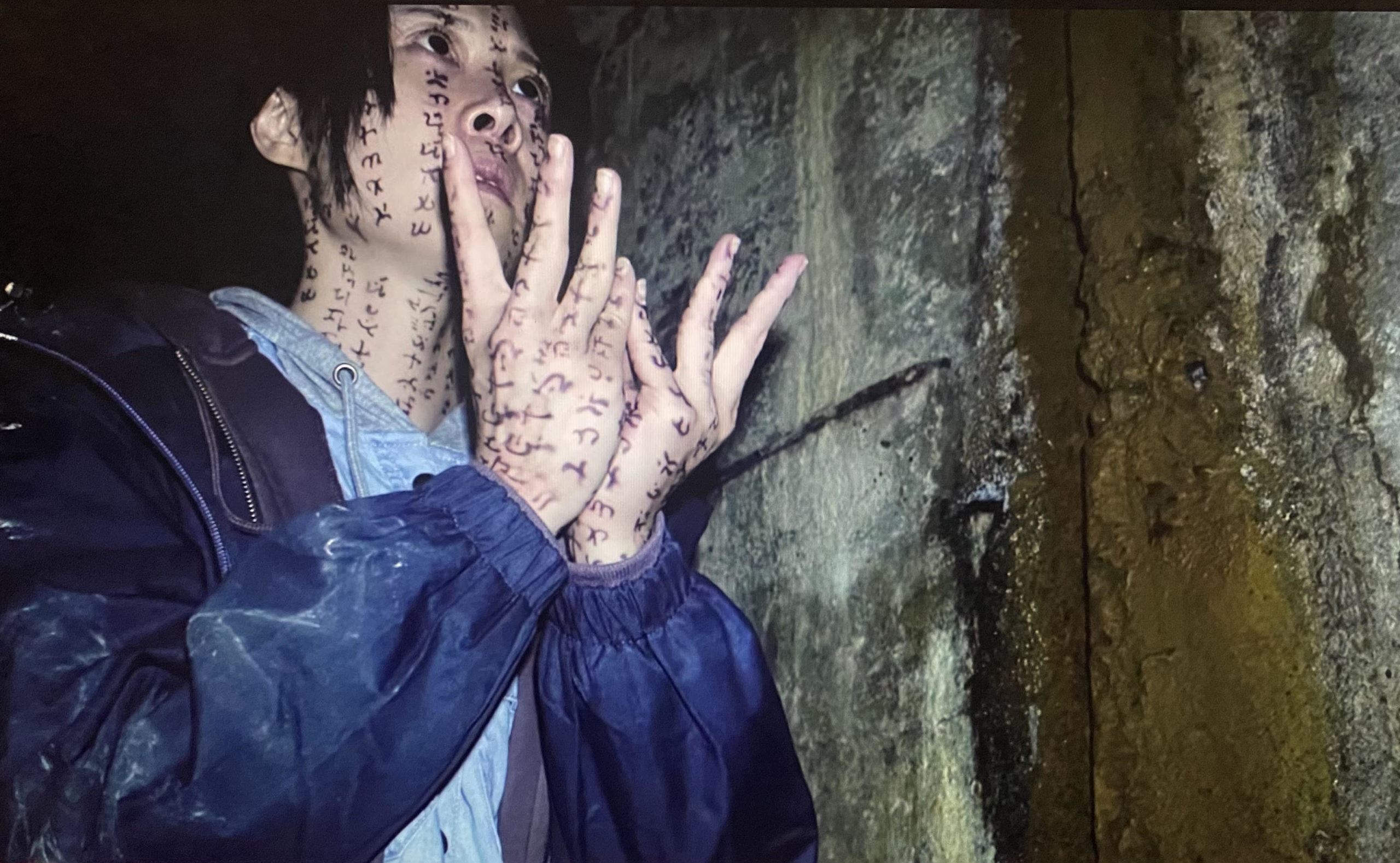 A girl with writings on her face and hands walking forward