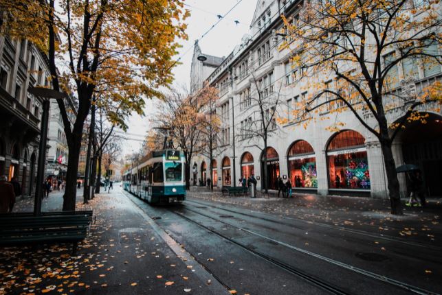 A street with shops at the side and a train in the middle