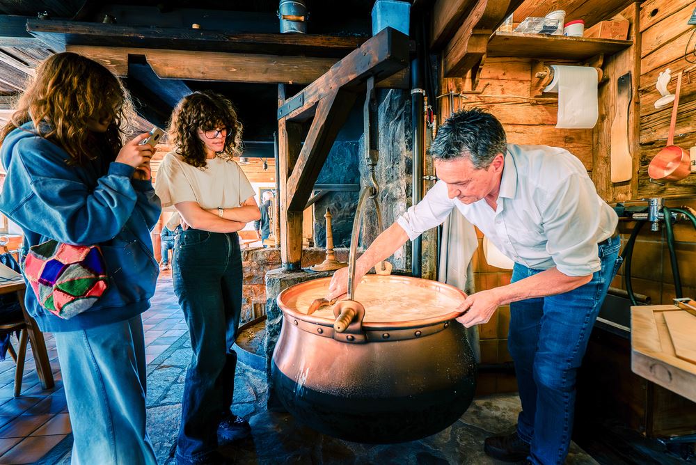 A man making cheese and two girls watching