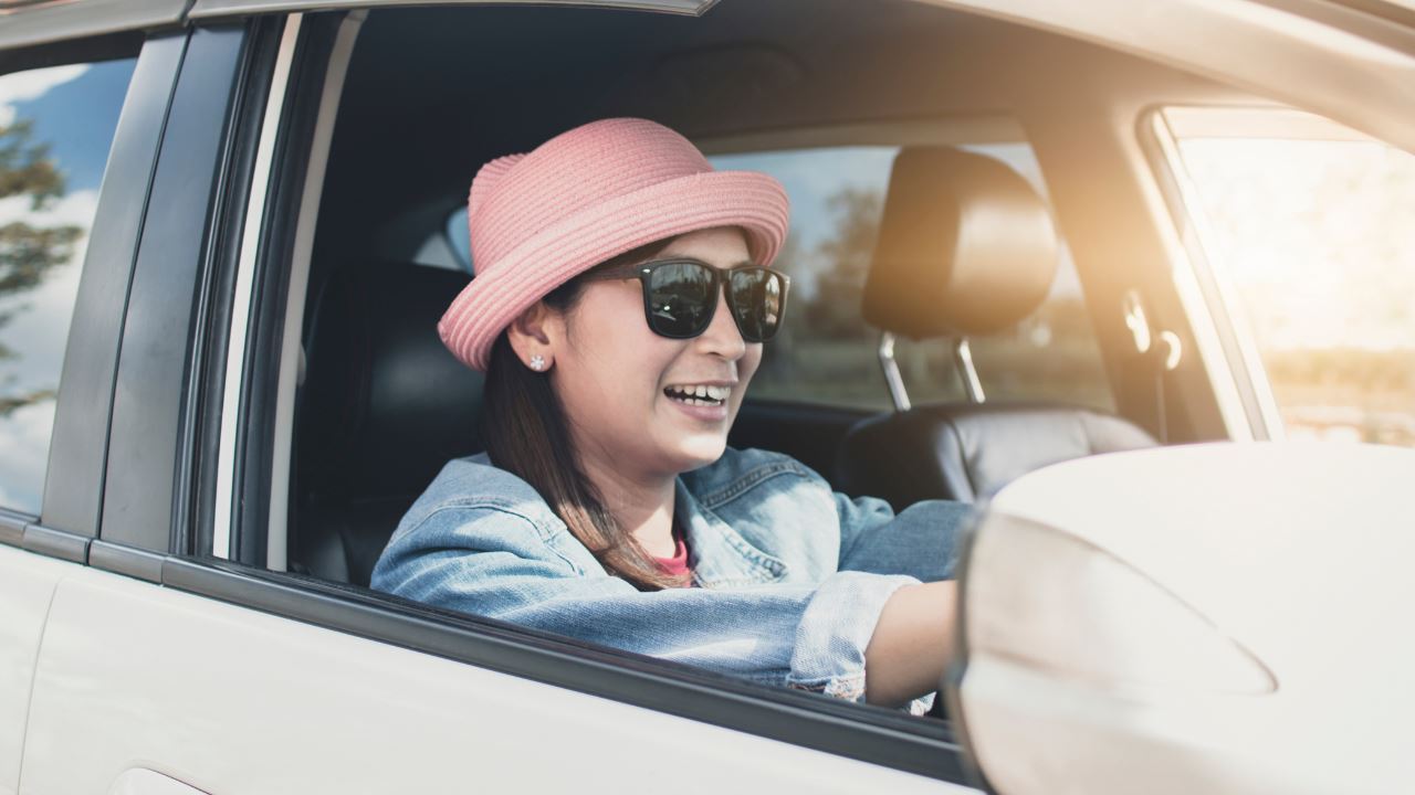 Asian woman in pink hat smiling while driving
