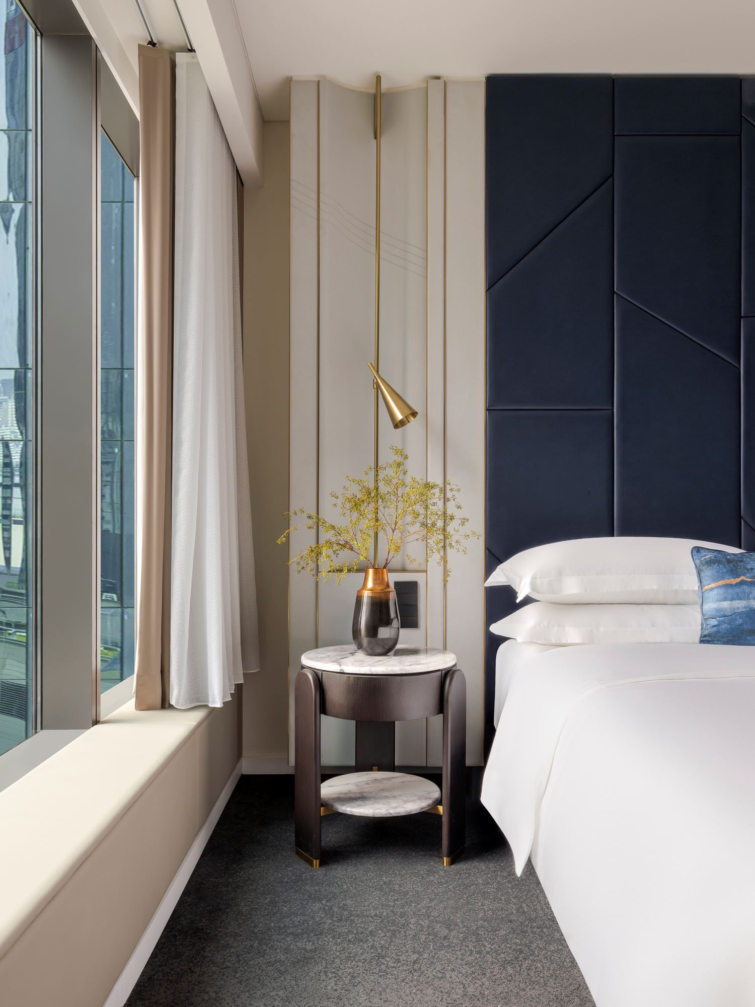 Elegant interior featuring the bedside and decor of an Essential room at Kimpton Naluria Kuala Lumpur