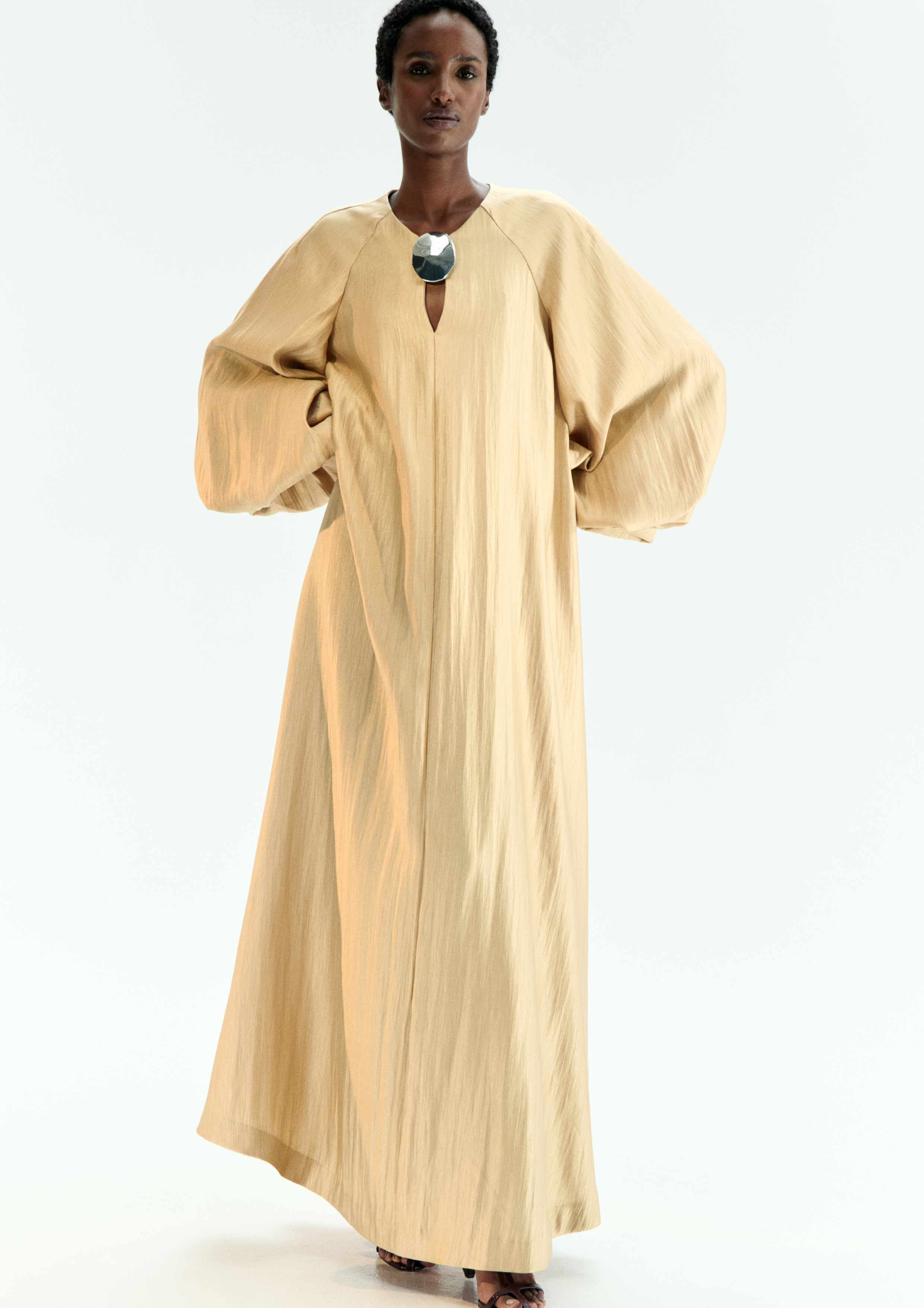 A model posing in a beige kaftan