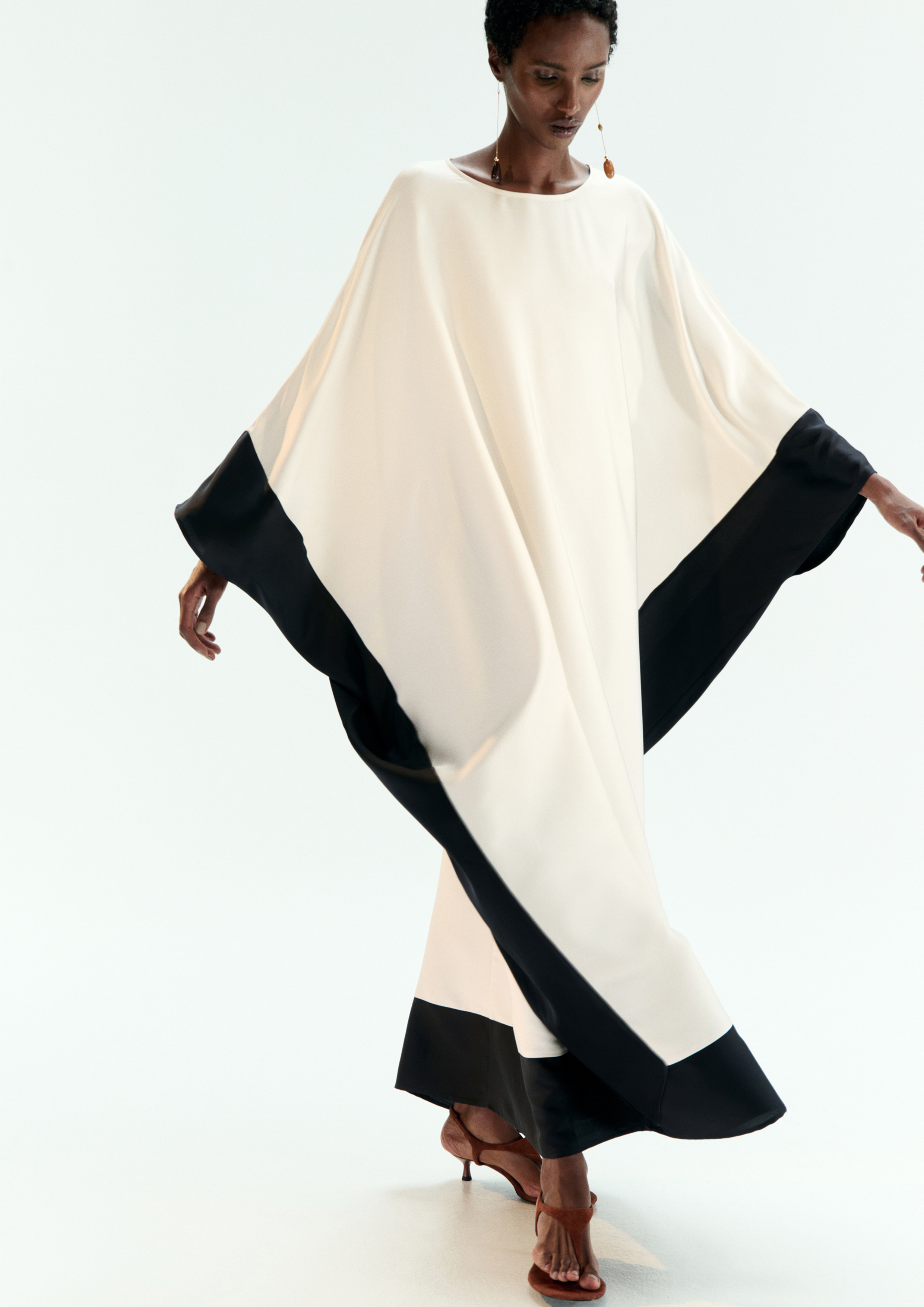 A model posing in a black and white kaftan