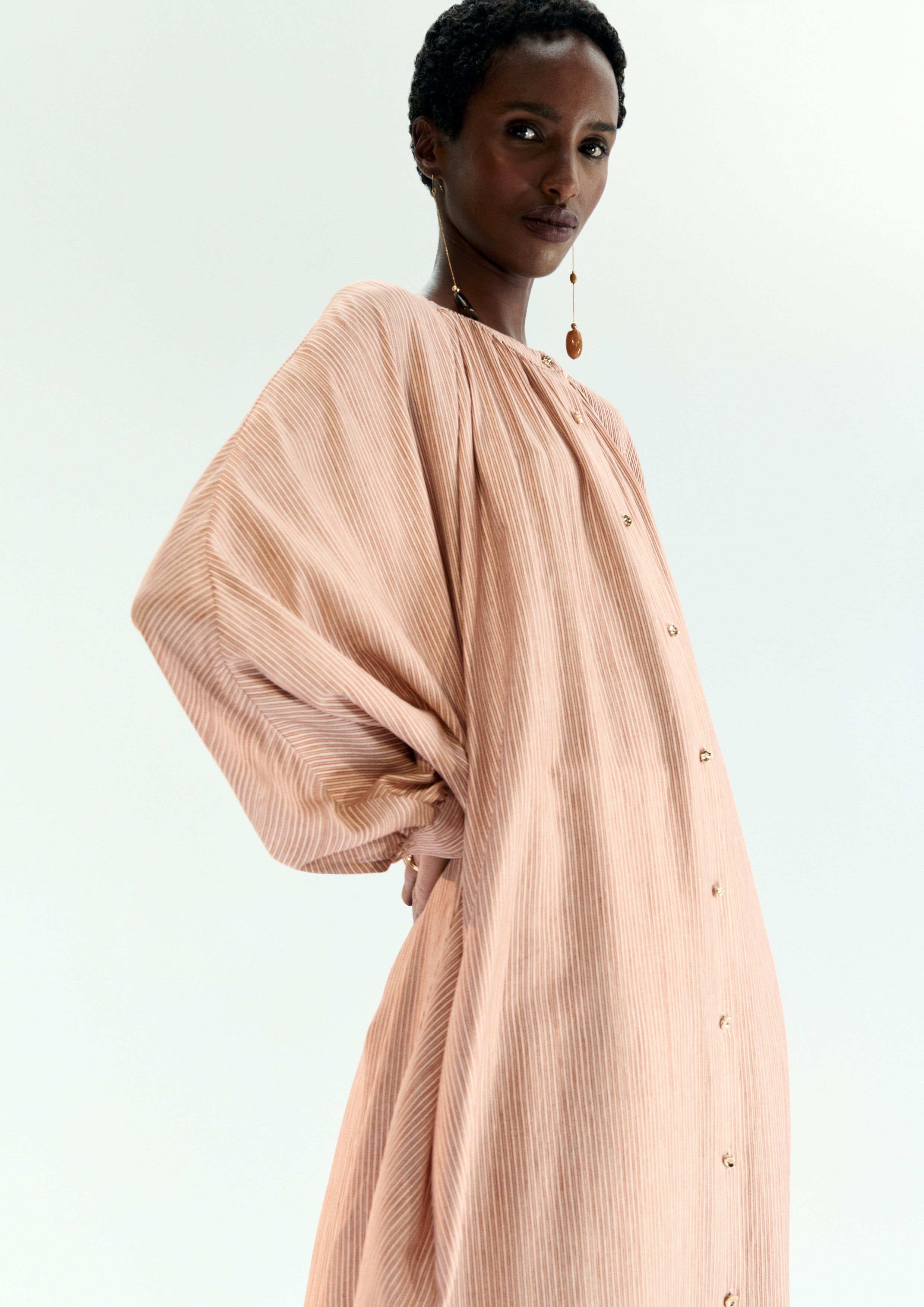 A model posing in a soft nude kaftan