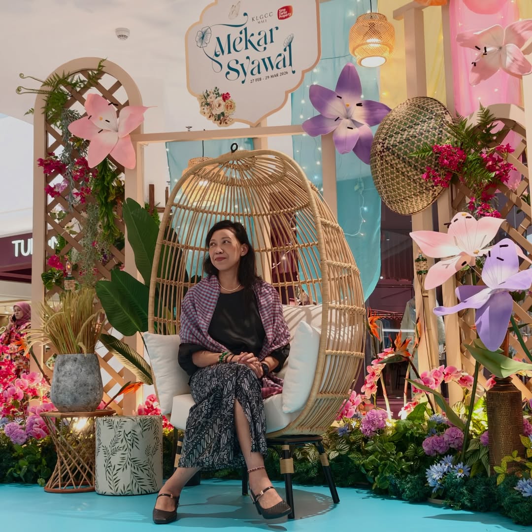 A lady posing at a seating area with flowers