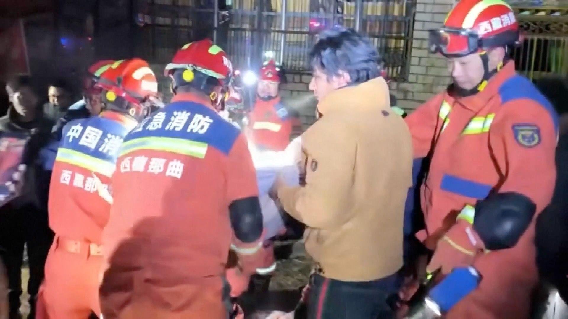 消防员协助救援西藏巴青县地震中的伤者。